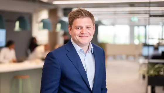 James Corrigan, UK Managing Director, Infrastructure, smiling in a softly lit office interior